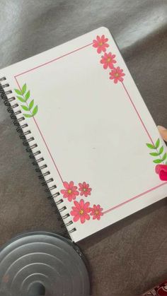 a hand holding a notebook with pink flowers on it