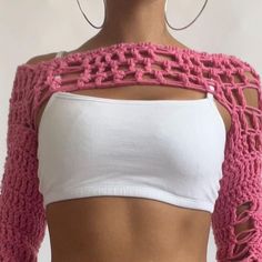 a woman wearing a pink crochet crop top and silver hoop earrings with her back to the camera