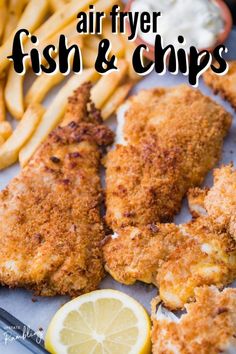 air fryer fish and chips on a tray with lemon wedges next to them