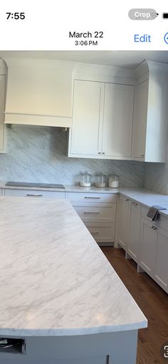 an iphone photo of a kitchen with white cabinets and marble counter tops on the phone