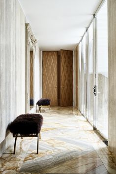 the hallway is lined with marble walls and flooring, along with two benches on either side