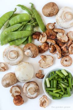 mushrooms, green beans and snap peas on a white surface