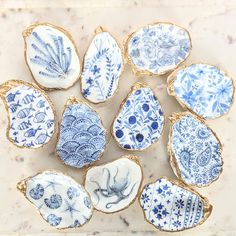 twelve blue and white porcelain dishes with gold rims on a marble countertop in the shape of seashells