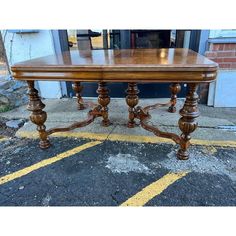 a wooden table sitting on top of a parking lot next to a building with yellow lines