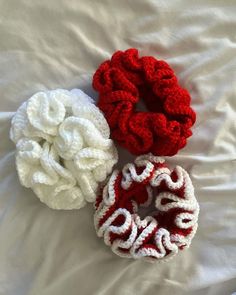 three crocheted scrunffles laying on top of a white bed next to each other