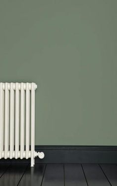 a white radiator sitting on top of a hard wood floor next to a green wall