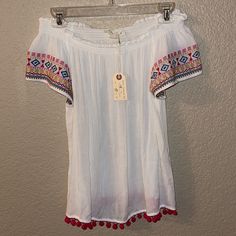 Nwt Stretchy And Off Of The Shoulder Embroidery Sleeve Detail With Tassels On The Waist Size Medium Such A Cute Top! White Short Sleeve Top With Embroidered Hem, White Embroidered Hem Top With Short Sleeves, White Bohemian Tops With Geometric Embroidery, White Casual Peasant Top With Floral Embroidery, Casual White Peasant Top With Floral Embroidery, White Tops With Embroidered Hem For Beach, White Short Sleeve Peasant Top For Summer, White Embroidered Hem Top For Beach, White Blouse With Geometric Embroidery For Summer