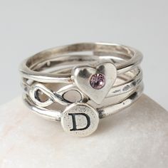 "Don't you just \"love\" this?! Stack the love and get one ring to represent each person in your family. Our heart birthstone ring is perfect for the mother or grandmother of one, or to wear yourself to represent your own birthstone. Wear just one or add more to your stack to represent the favorite people in your life that mean so much to you! This listing is for one stackable sterling silver and 2mm Swarovski crystal birthstone heart ring. Want to add more shapes to your stack? Create your own Adjustable Anniversary Rings With Heart Charm, Personalized Pink Ring For Birthday, Anniversary Ring With Heart Charm, Adjustable Stackable Rings For Valentine's Day, Personalized Pink Birthday Ring, Sterling Silver Heart Ring For Birthday And Valentine's Day, Cute Rings For Anniversary On Valentine's Day, Personalized Heart Promise Ring, Cute Rings For Valentine's Day Anniversary