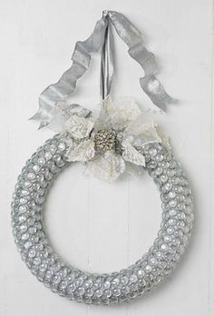 a wreath hanging on the wall with silver and white ribbon around it's edge