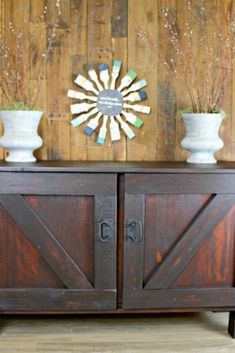 two white vases sitting on top of a wooden cabinet next to a wall mounted clock