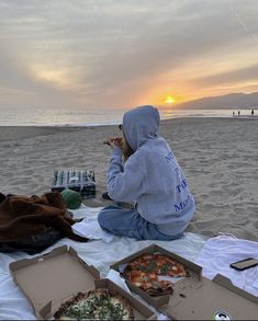 a person sitting on the beach eating pizza