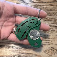 a person holding a green keychain with a coin in it