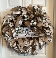 a wreath that says southern charm hanging on the front door with flowers and ribbon around it