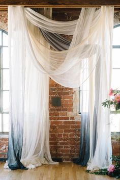 an instagram photo of a room with sheer curtains and brick walls