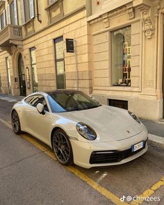 a white sports car parked on the side of the road in front of a building