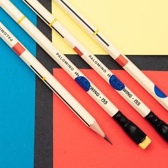 four pens are lined up next to each other on a colorful tablecloth with black and white stripes