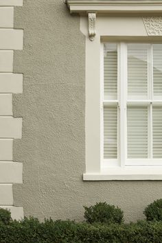 a cat sitting on the ledge of a window sill in front of a house