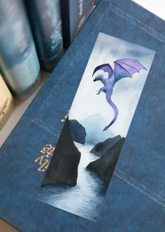 a book with an image of a dragon on the cover and some books behind it