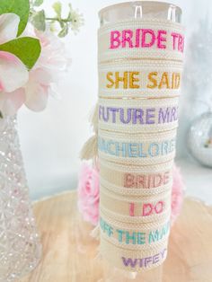 a white vase with pink flowers and a message wrapped around it on top of a wooden table