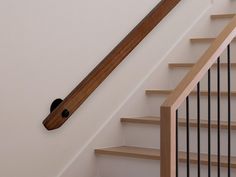 a wooden hand rail on the side of a stair case next to a banister