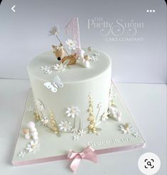 a white cake decorated with flowers, butterflies and a baby's name on it