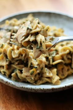 a spoon full of pasta with chicken and spinach in it on a white plate