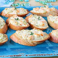 there are many breads with different toppings on the blue platter next to each other