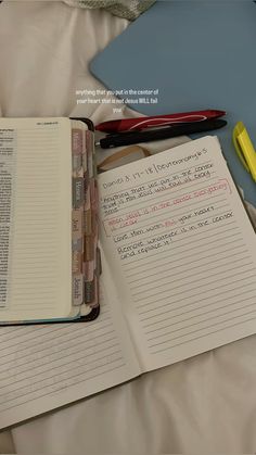 an open notebook sitting on top of a bed next to a pair of yellow scissors