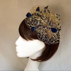 Delicate gold and navy fascinator perfect for the guest who wants something fairly understated. This design is a beautiful selection of glass effect leaves and flowers clustered together amongst a fine layer of veiling and set onto a gold ribbon base tiara band.As with all our designs, this piece can be made in any colour combination and set onto either a band or a comb which you can state either before or after orderingAs a online shop item this item can be made exact to the sample in the pictu Gold Round Crown Headpiece For Weddings, Gold Wedding Headpiece With Round Crown, Gold Crown Costume Headpiece For Weddings, Gold Crown Headpiece For Wedding, Gold Costume Hats With Structured Crown For Evening, Gold Headpiece With Round Crown For Party, Gold Round Crown Headpiece For Party, Gold Pinched Crown Headpiece For Kentucky Derby, Gold Headband For Kentucky Derby