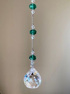 a crystal hanging ornament with green and white stones on it's side