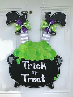 a trick or treat door hanger with candy in a witches caulder and the words trick or treat on it