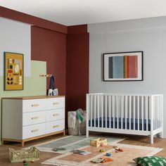 a baby's room with a crib, dresser and toy chest in it