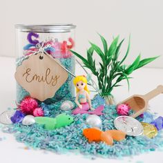 a glass jar filled with lots of sea shells and other items next to a plant