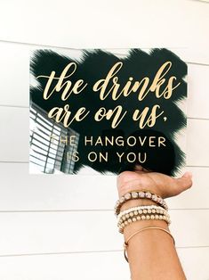 a person holding up a sign that says the drinks are on us he hangover is on you