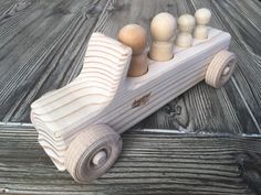 a toy car made out of wood sitting on top of a wooden floor