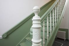 a white banister next to a green painted stair case in a room with carpeted flooring