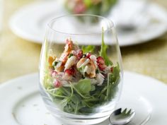 a glass filled with salad sitting on top of a white plate