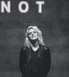 a black and white photo of a woman standing in front of a sign that says not to