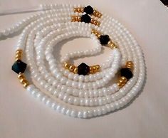 a white beaded necklace with black beads and gold accents on a white tablecloth