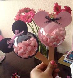 a person is holding up some candy in front of minnie mouse ears and pink flowers