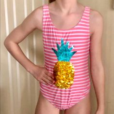 a girl wearing a pink and white striped shirt with a gold pineapple on it