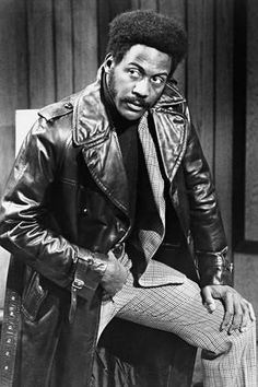 a man sitting on top of a chair wearing a leather jacket