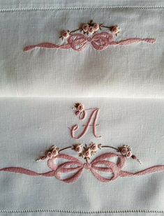 two embroidered monograms on white linen with pink ribbons and flowers in the middle