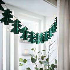 a green garland with trees hanging from it's sides next to a potted plant