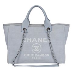 Authentic, pre-loved Chanel Deauville shoulder bag tote. Features baby blue canvas, silver-tone hardware, leather handles with dual shoulder straps with chain-link and blue trim, white embroidered logo embellishment at front face, tonal canvas lining, and two pockets on interior walls along with a zipper top closure. Authenticity RFID: JHP3913G Made in Italy Strap drop: 14" Luxury Blue Canvas Shoulder Bag, Luxury Blue Canvas Bag, Canvas Tote Shoulder Bag With Silver-tone Hardware, Everyday Use Canvas Bag With Silver-tone Hardware, Canvas Tote Bag With Silver-tone Hardware, Canvas Bags With Palladium Hardware For Daily Use, Chanel Tote, Chanel Shoulder Bag, Chanel Logo