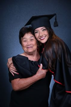 an older woman in graduation gown hugging her younger sister, who is wearing a black cap and gown