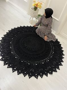 a woman sitting on the floor next to a black doily