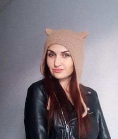 a woman wearing a jacket and a knitted bear hat is posing for the camera