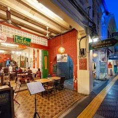 the inside of a restaurant with tables, chairs and signs on the outside wall at night