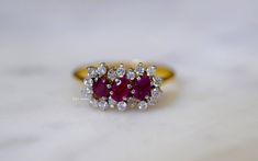 Metal: 18kt Yellow Gold Stone: Diamond And Ruby Stone Shape: Round And Oval Approximate Diamond Total Weight: .32 ctw Approximate Ruby Weight: .61 ctw Ring Size: 7 Sizable: Yes. Please state size in size/personalization box. Weight of entire piece with stones: 3.30 grams Measurements of Top Part Of Ring: 14mm Long and 8.31mm Wide Height Of Ring: 24.29 mm Shoulder Width: 1.33 mm Luxury Ruby Cluster Ring With Diamonds, Luxury Cluster Ruby Ring With Diamonds, Cluster Diamond Ring With Vvs Clarity And Ruby, Timeless Diamond Ruby Anniversary Ring, Formal 14k Gold Ruby Ring With Single Cut Diamonds, Timeless Diamond Ruby Ring For Anniversary, Exquisite Diamond Multi-stone Cluster Ring, Classic Yellow Gold Ruby Ring With Single Cut Diamonds, Ruby Ring With Diamond Cluster And Brilliant Cut